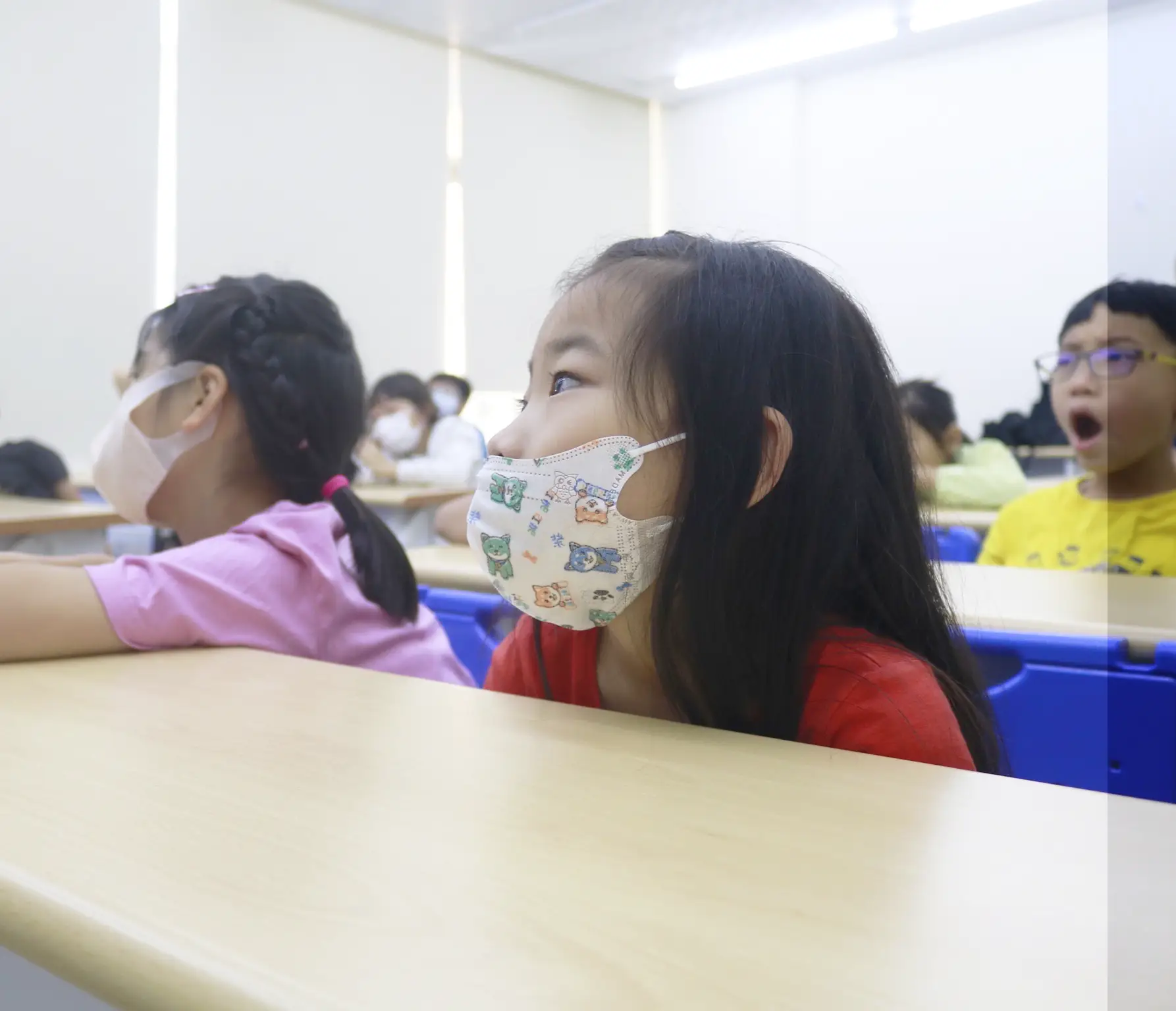 一位戴著口罩的女同學認真聽課的特寫。
