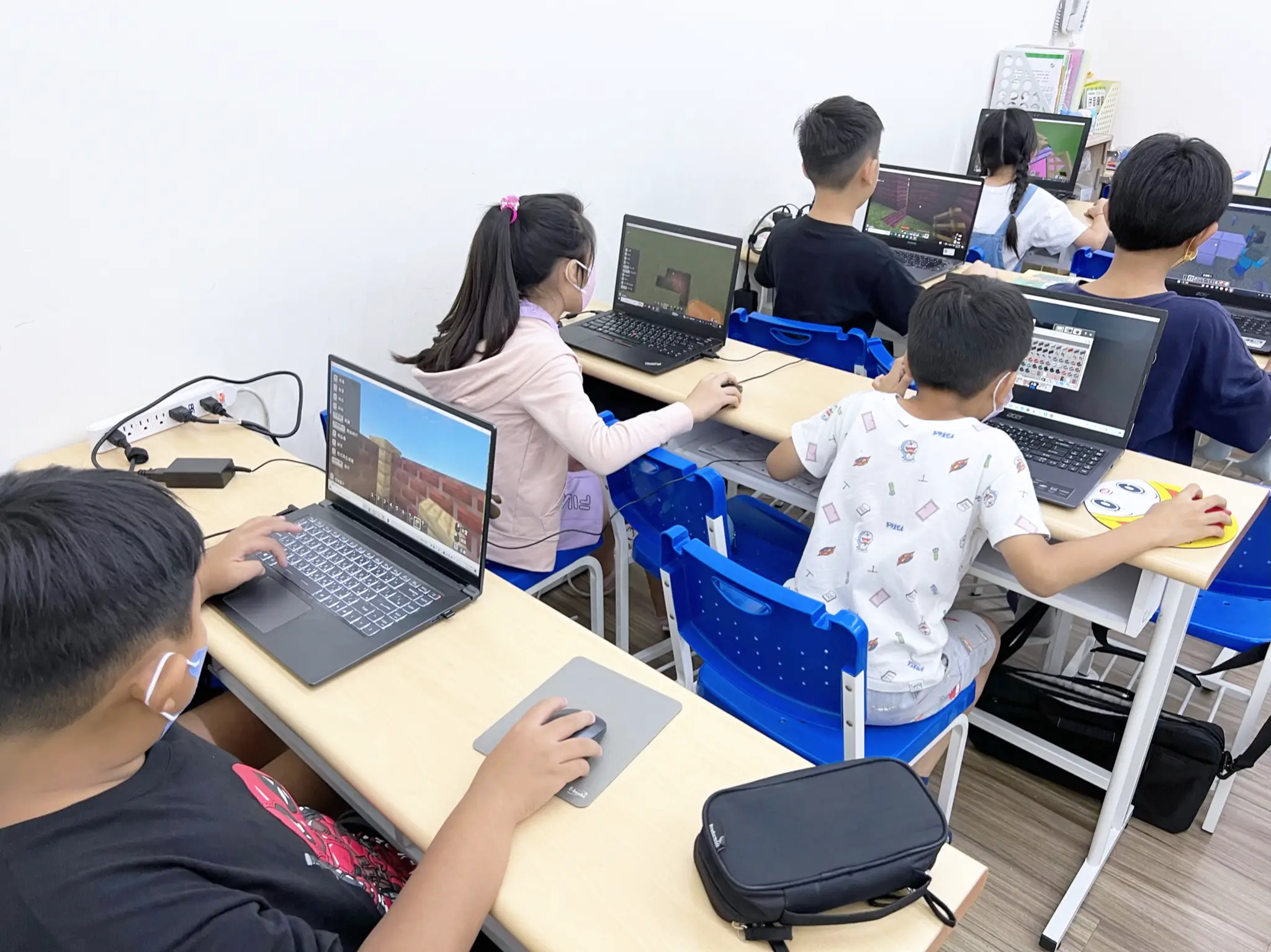 教室中的同學們正在利用電腦遊玩Minecraft教育版。