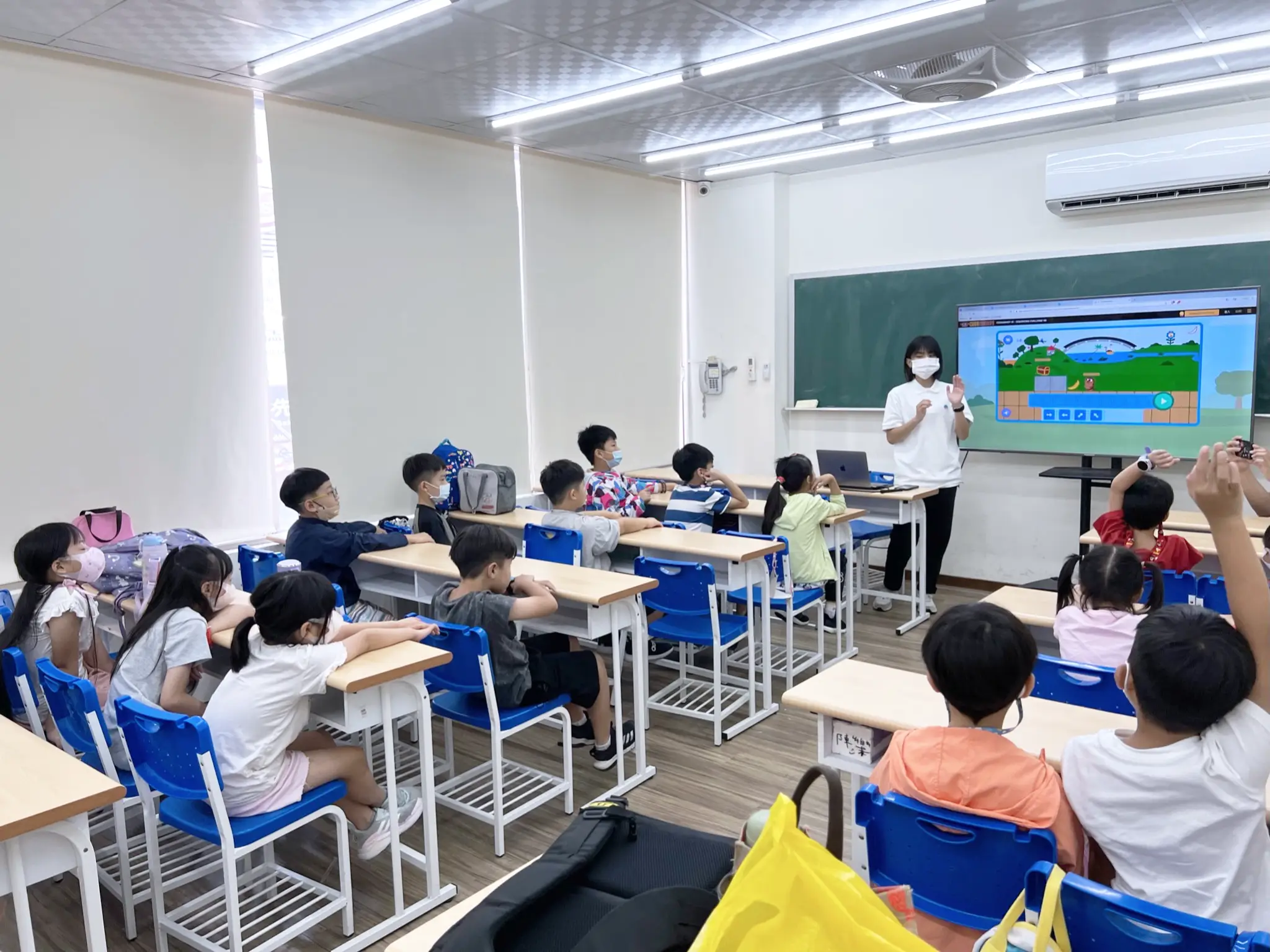 一位穿著白色Polo衫的女老師正在和同學們講解課程。